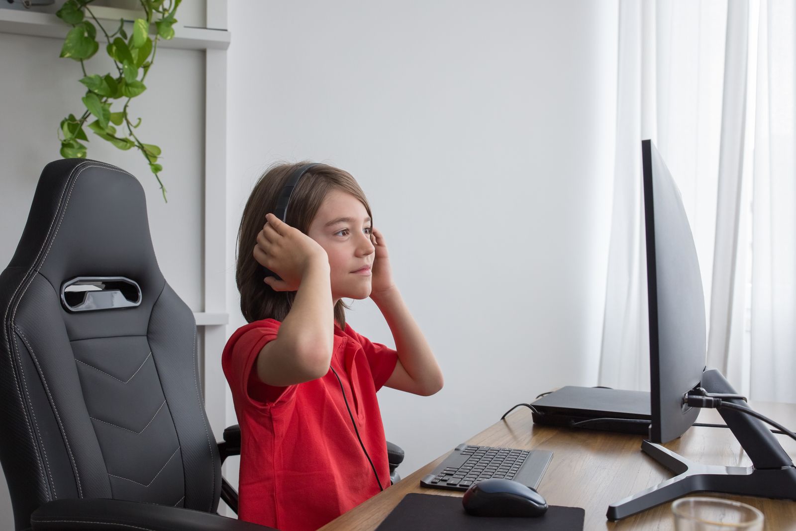 En gutt setter på seg headset foran PC-en hjemme